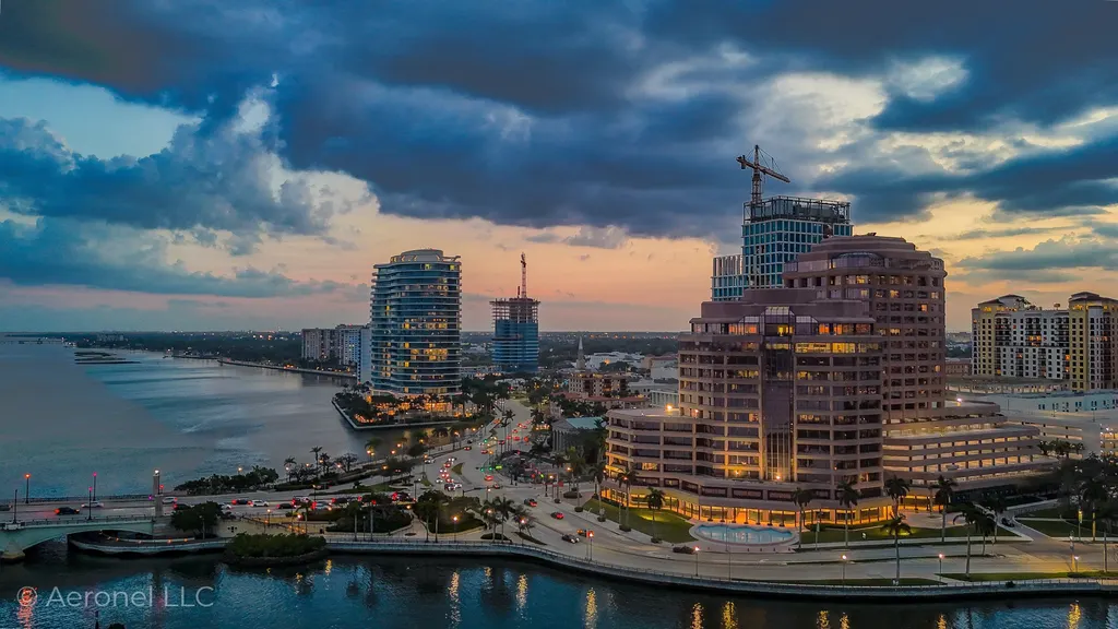 The West Palm Beach waterfront at dusk, city and bridge lights reflecting on the Intracoastal, photographed by Aeronel